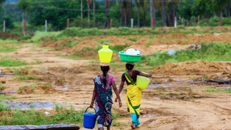 Women in India carrying water back through the fields