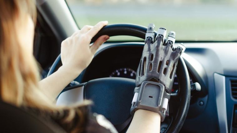 A robotic prosthetic hand holding the steering wheel of a car