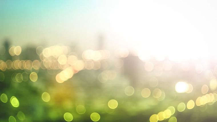 Abstract image of blurred colourful lights against a green, natural sunrise background