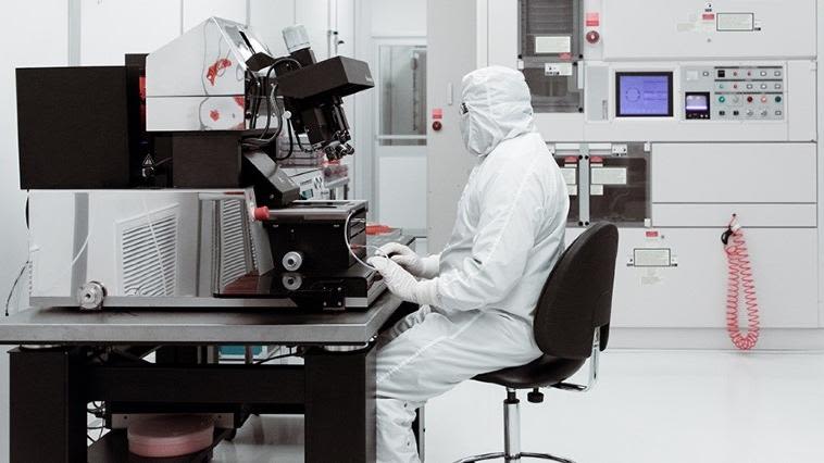 Scientist in protective clothing working at a high-tec equipment station in a lab