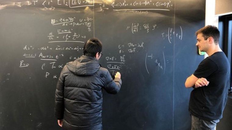 Two theoretical physicists in the Department of Physics working at a blackboard