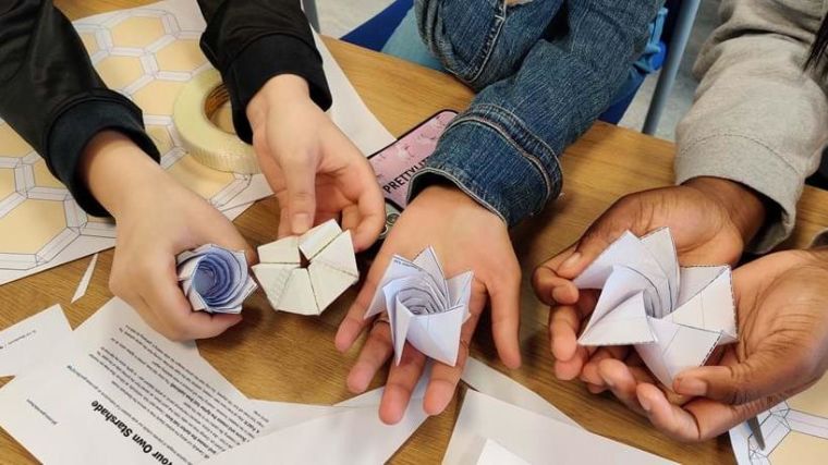 Student hands holding the origami models made at an Uncover workshop