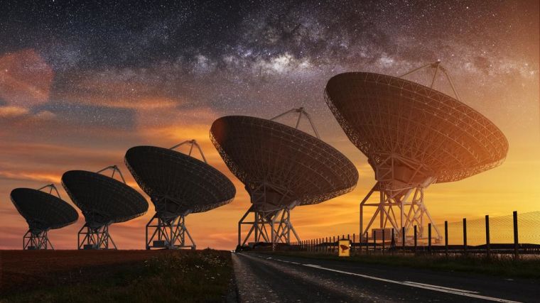 Five radio telescopes pointing at the sky with the Milky Way beyond